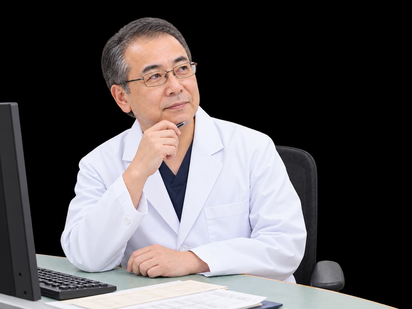 パソコンの前でレセプト業務について考える50代の男性医師